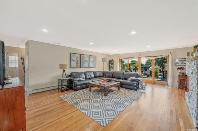 living room featuring a fireplace, light hardwood / wood-style flooring, and a baseboard radiator