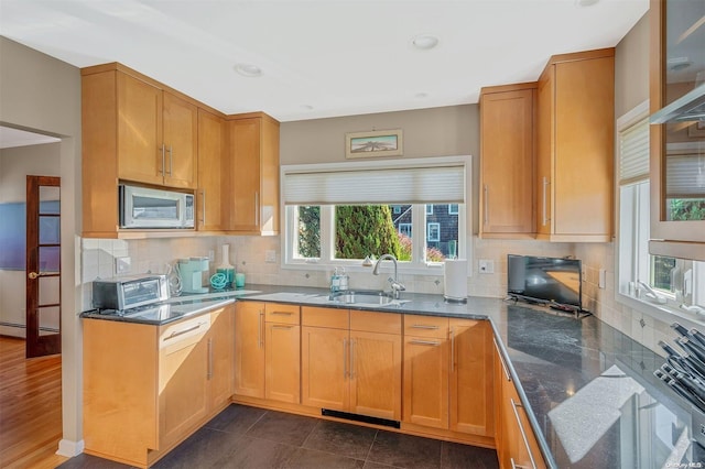 kitchen featuring decorative backsplash, white microwave, baseboard heating, sink, and dark hardwood / wood-style floors