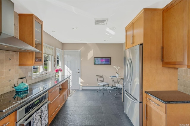 kitchen featuring decorative backsplash, wall chimney range hood, stainless steel appliances, and baseboard heating