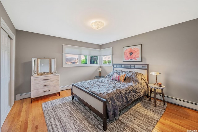 bedroom with a closet, light wood-type flooring, and a baseboard heating unit