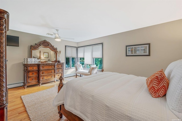 bedroom with ceiling fan, light wood-type flooring, and a baseboard heating unit