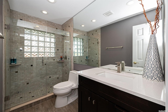 bathroom featuring hardwood / wood-style floors, vanity, toilet, and walk in shower