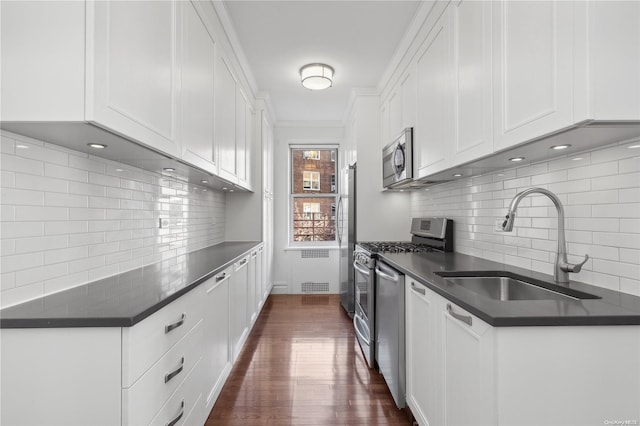 kitchen with sink, dark wood-type flooring, stainless steel appliances, backsplash, and white cabinets