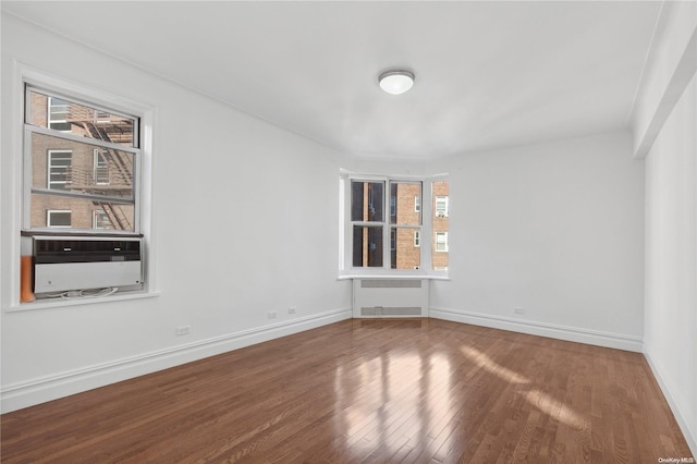 empty room with radiator heating unit, cooling unit, and wood-type flooring