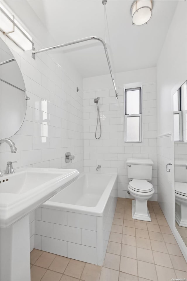 bathroom featuring tile patterned flooring, toilet, tile walls, and tiled shower / bath