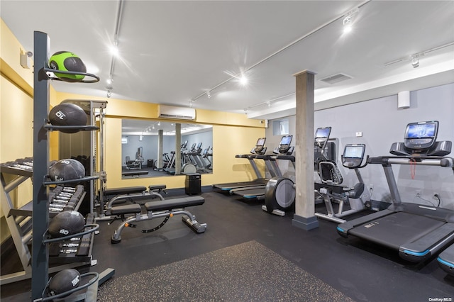 exercise room with a wall mounted air conditioner and rail lighting