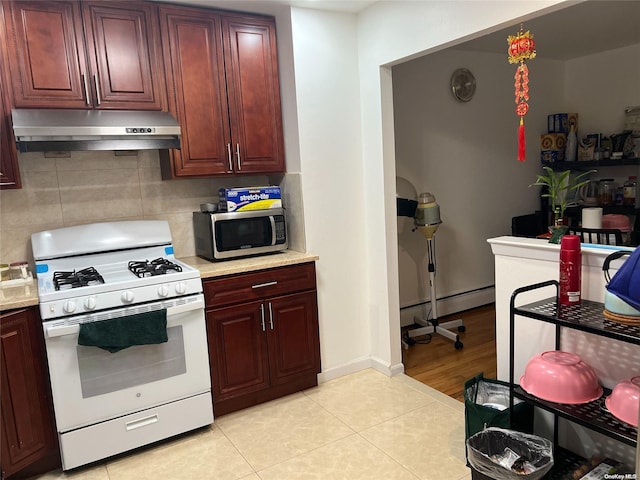 kitchen with tasteful backsplash, baseboard heating, white gas stove, and light tile patterned flooring