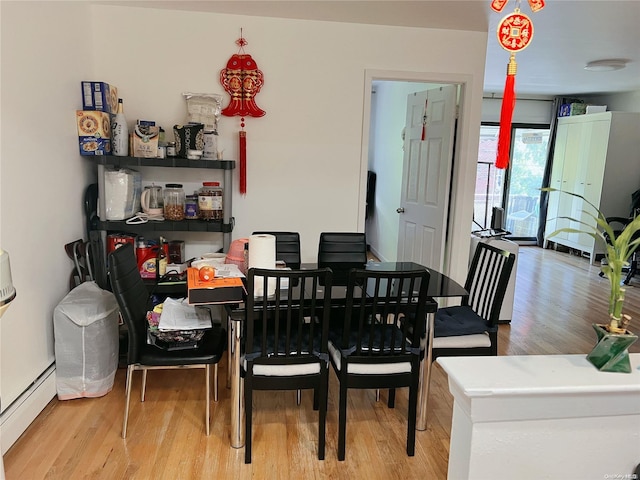 dining space with hardwood / wood-style floors and a baseboard heating unit