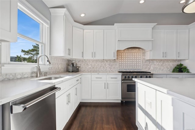 kitchen with appliances with stainless steel finishes, tasteful backsplash, vaulted ceiling, sink, and white cabinets