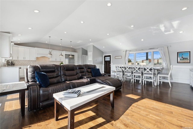 living room with sink, dark wood-type flooring, and vaulted ceiling