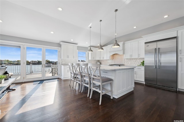 kitchen featuring white cabinetry, hanging light fixtures, a kitchen island, stainless steel built in refrigerator, and a water view