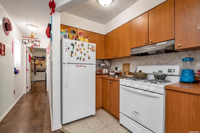 kitchen with tasteful backsplash, sink, light hardwood / wood-style floors, and white appliances