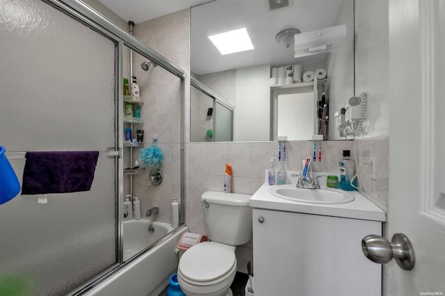 full bathroom with tasteful backsplash, vanity, shower / bath combination with glass door, tile walls, and toilet