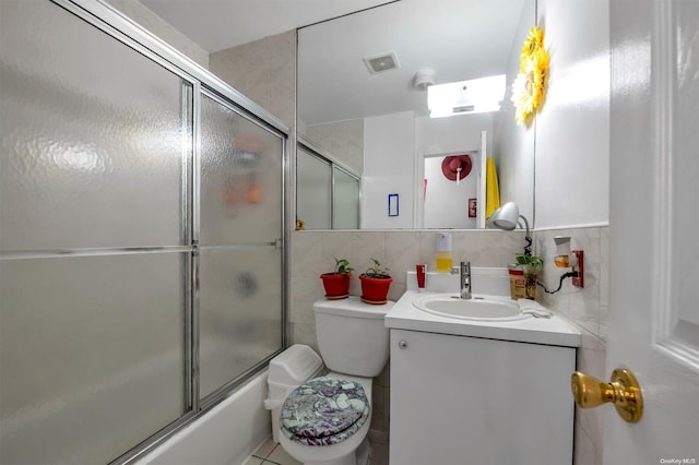 full bathroom with combined bath / shower with glass door, backsplash, vanity, tile patterned flooring, and toilet