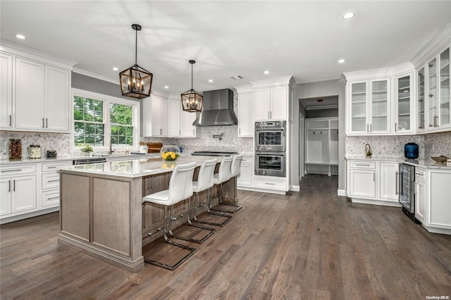 kitchen with white cabinets, wall chimney range hood, stainless steel appliances, and dark wood-type flooring