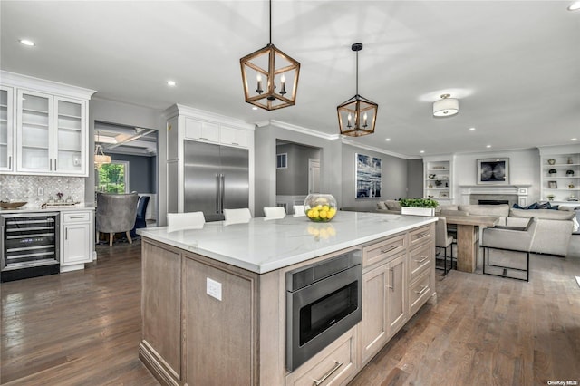 kitchen with white cabinetry, dark wood-type flooring, hanging light fixtures, stainless steel appliances, and light stone counters