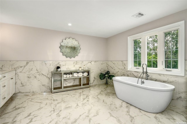 bathroom with vanity, tile walls, and a tub