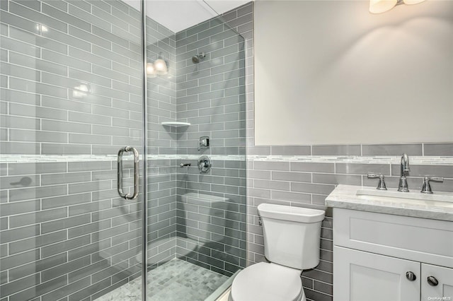 bathroom with vanity, a shower with door, toilet, and tile walls