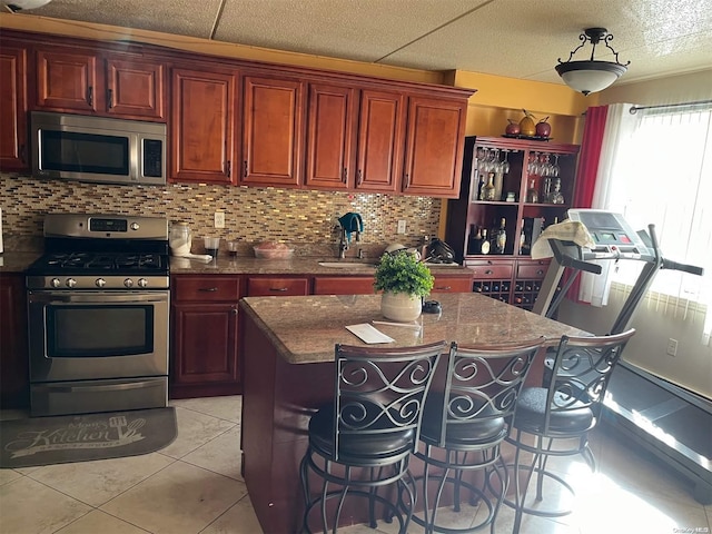 kitchen with a center island, a kitchen breakfast bar, tasteful backsplash, light tile patterned flooring, and appliances with stainless steel finishes