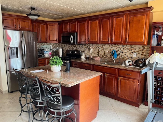 kitchen featuring light stone countertops, stainless steel appliances, light tile patterned floors, a breakfast bar area, and a kitchen island