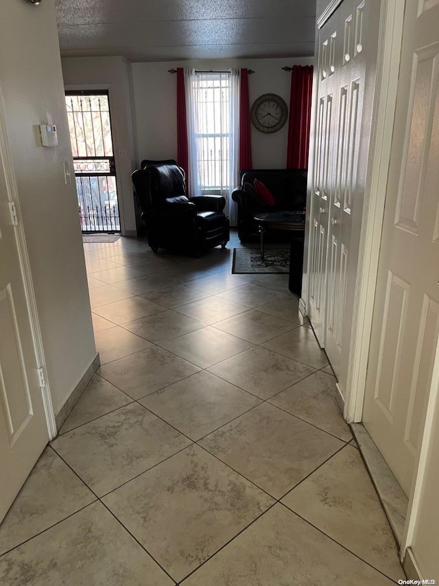 hall with a healthy amount of sunlight, light tile patterned floors, and a textured ceiling