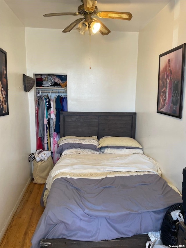 bedroom with ceiling fan, wood-type flooring, and a closet