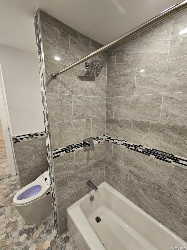 bathroom with tiled shower / bath combo, toilet, and tile walls