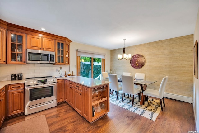 kitchen featuring dark wood-type flooring, an inviting chandelier, hanging light fixtures, kitchen peninsula, and stainless steel appliances