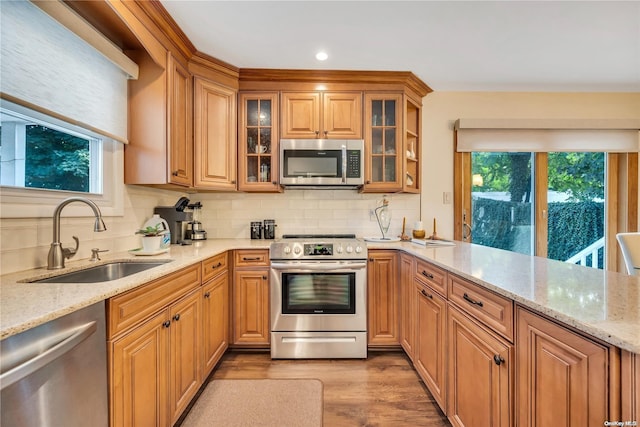 kitchen with plenty of natural light, sink, appliances with stainless steel finishes, and light hardwood / wood-style flooring