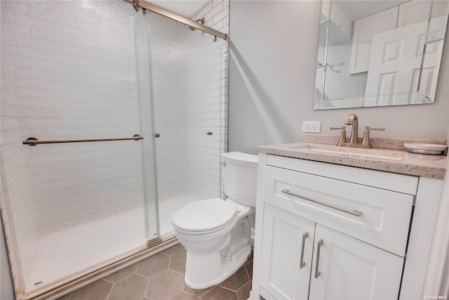 bathroom with tile patterned flooring, vanity, toilet, and a shower with shower door