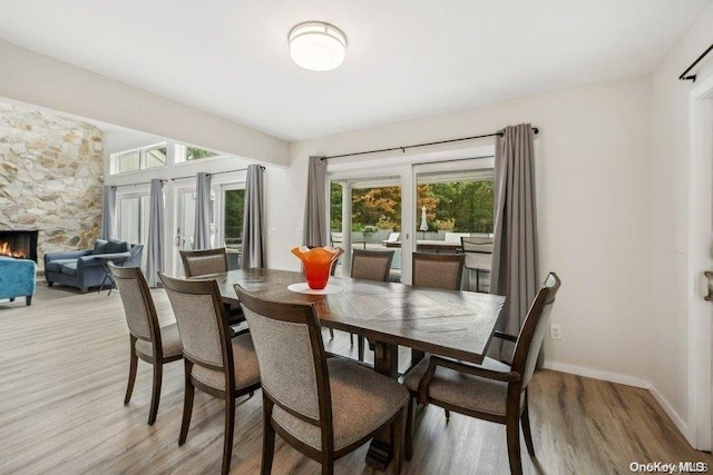 dining area featuring light hardwood / wood-style floors and a stone fireplace