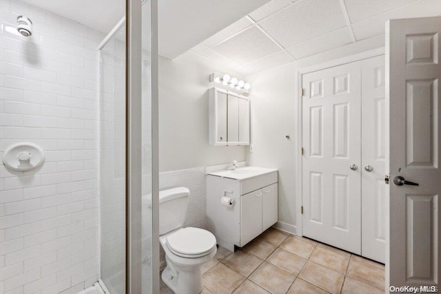 bathroom featuring a paneled ceiling, tile patterned floors, an enclosed shower, vanity, and toilet