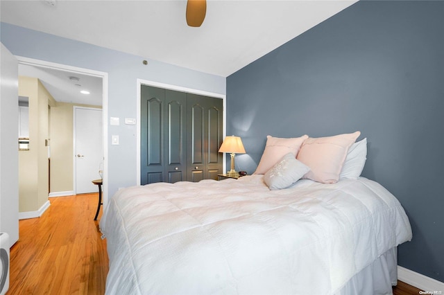 bedroom with ceiling fan, wood-type flooring, and a closet