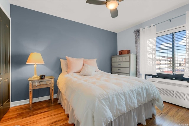 bedroom with a closet, ceiling fan, radiator heating unit, and light wood-type flooring