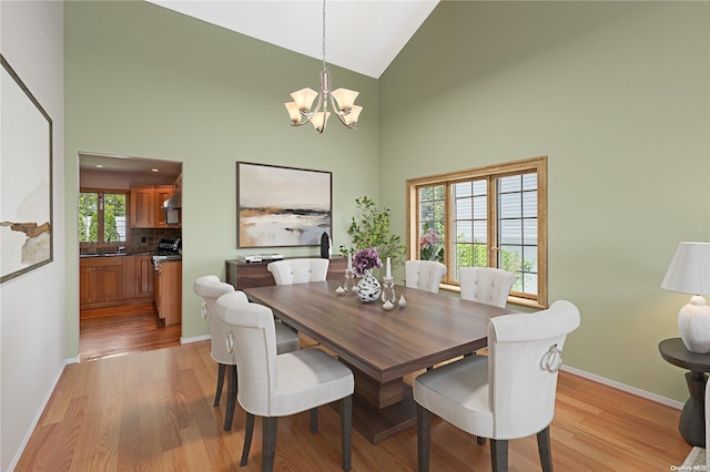 dining space featuring high vaulted ceiling, light hardwood / wood-style floors, sink, and a chandelier