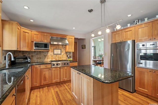 kitchen with sink, decorative light fixtures, extractor fan, a center island, and stainless steel appliances