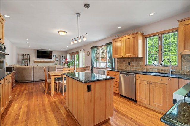 kitchen featuring pendant lighting, appliances with stainless steel finishes, sink, light wood-type flooring, and a center island