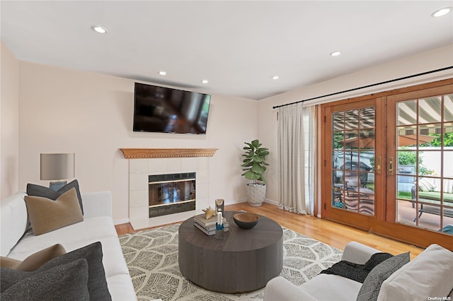 living room with a tile fireplace and light hardwood / wood-style floors