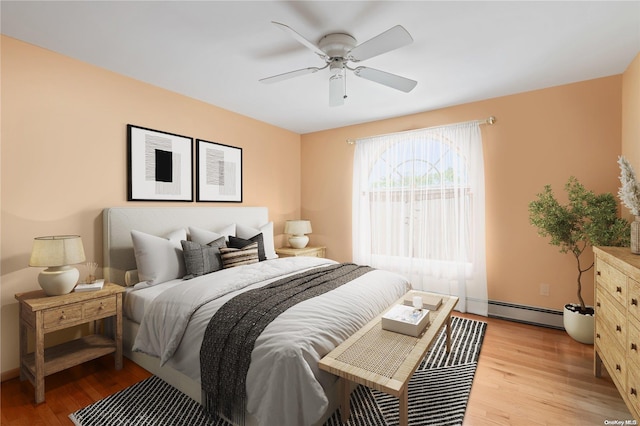 bedroom with ceiling fan, a baseboard heating unit, and light hardwood / wood-style floors