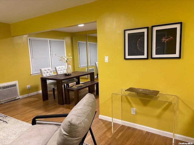 dining space featuring a wall mounted air conditioner and wood-type flooring