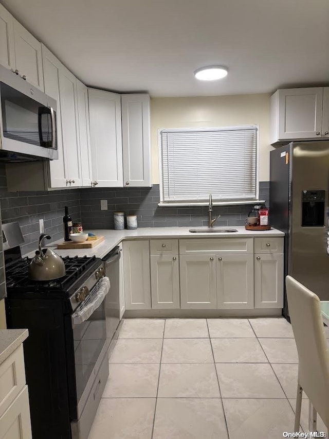 kitchen with backsplash, sink, white cabinets, and stainless steel appliances