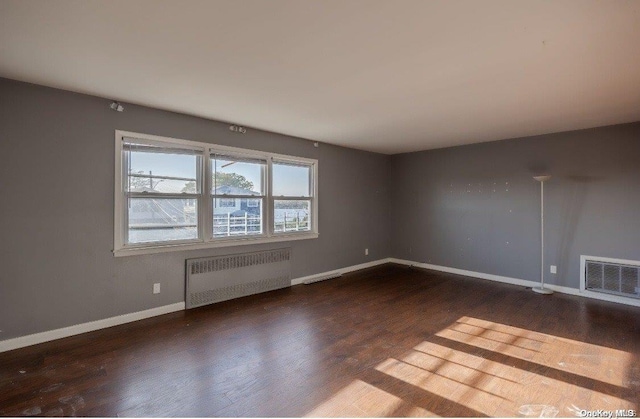 spare room featuring dark hardwood / wood-style floors and radiator