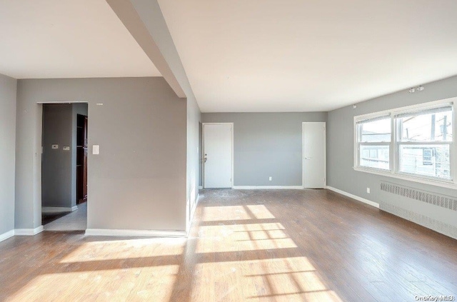 empty room featuring radiator heating unit and light hardwood / wood-style flooring