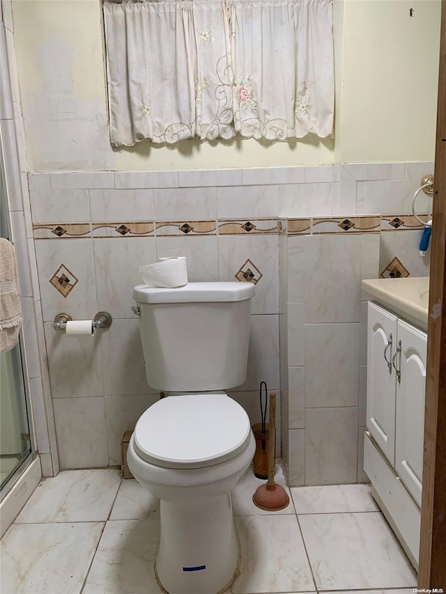 bathroom with vanity, an enclosed shower, tile walls, and toilet