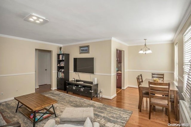 living room with wood-type flooring, an inviting chandelier, and ornamental molding