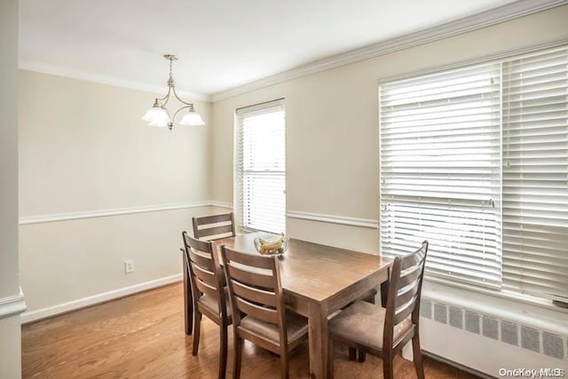 dining room with wood-type flooring, radiator heating unit, ornamental molding, and an inviting chandelier