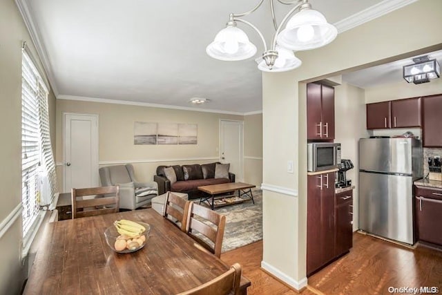 dining area with hardwood / wood-style flooring, crown molding, and a chandelier