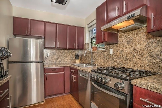 kitchen featuring backsplash, sink, stainless steel appliances, and light wood-type flooring