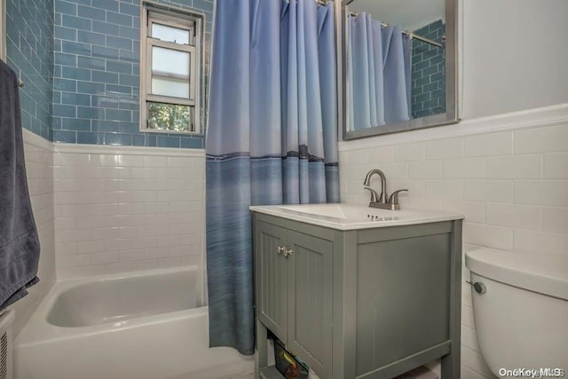 full bathroom featuring vanity, shower / bathtub combination with curtain, toilet, and tile walls