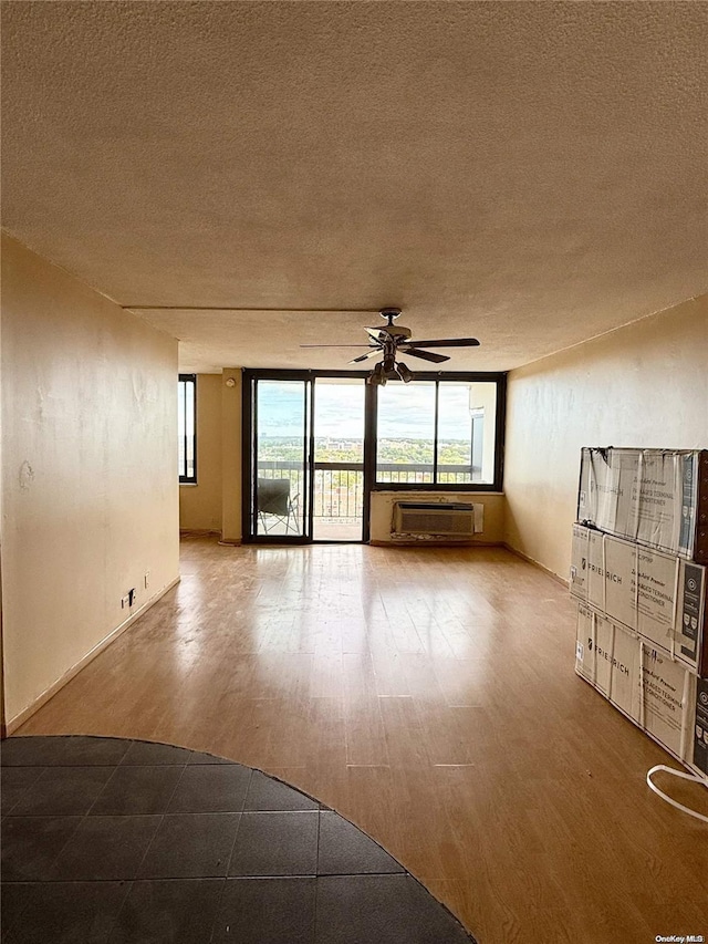 spare room with a wall mounted air conditioner, ceiling fan, wood-type flooring, and a textured ceiling